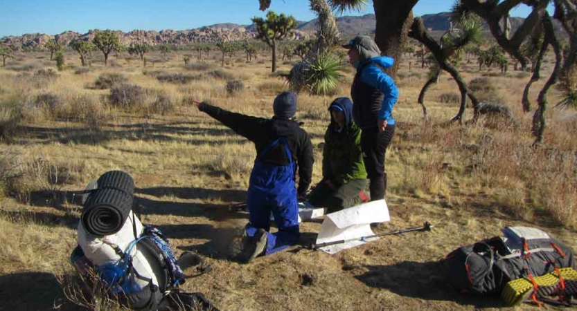 a group of veterans use maps to navigate on an outward bound backpacking course